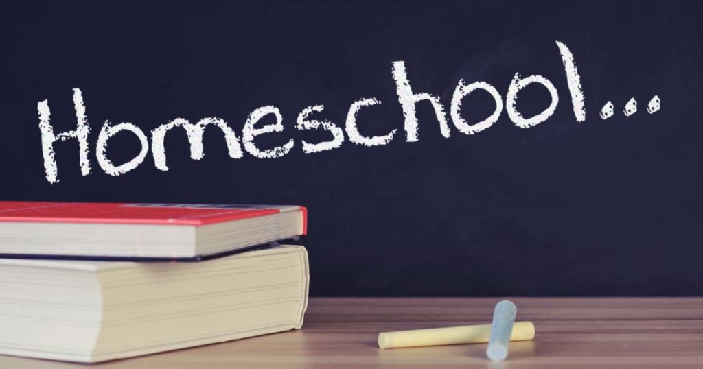 Matthew Davies image of school books and chalk on a table with a chalkboard in the background with the word Homeschool