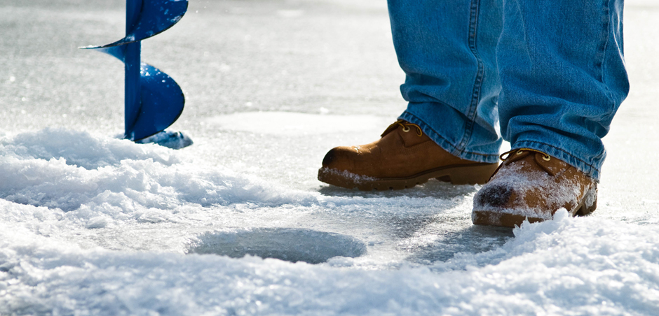 Matthew Davies image of a person standing on ice with an ice fishing hole.