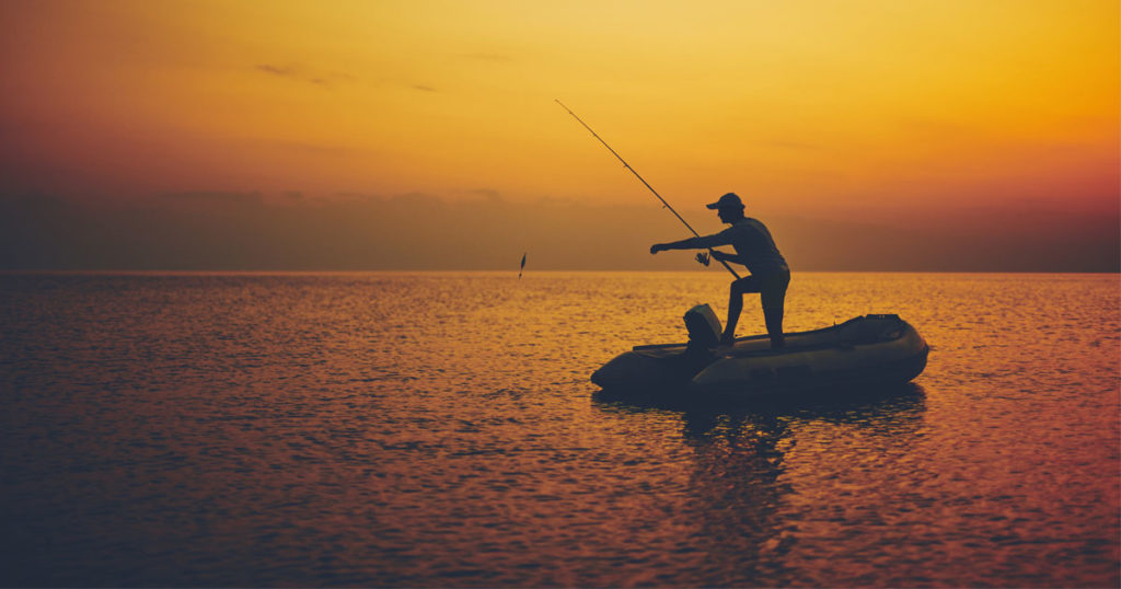 Matthew Davies image of a person fishing from a boat at sunset